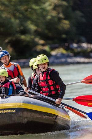 Kinder und Raftingguide paddeln gemeinsam auf der Saalach in Lofer