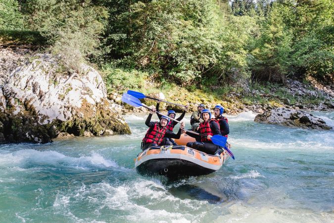 Raftinggruppe im orangefarbenen Boot zwischen Felsen der Saalach