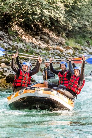 Raftinggruppe jubelt mit erhobenen Paddeln auf der Saalach