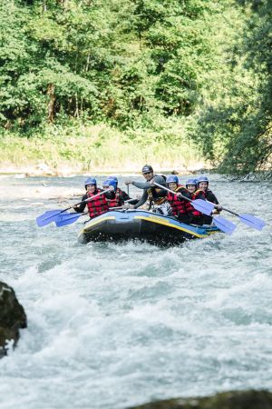 Raftinggruppe paddelt durch eine Stromschnelle der Saalach bei Lofer