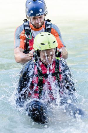 Raftingguide begleitet ein Kind im Wasser der Saalach bei Lofer