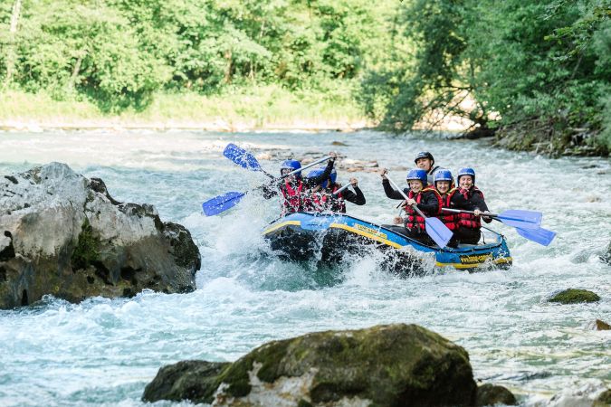 Raftingboot passiert eine Stromschnelle zwischen Felsen auf der Saalach