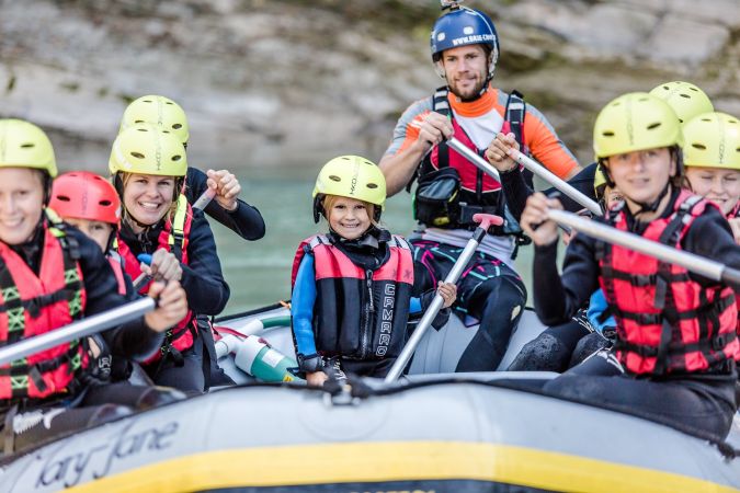 Kinder und Raftingguides sitzen gemeinsam im Boot in Lofer