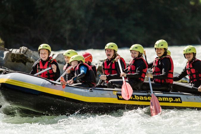 Familien lachen gemeinsam bei einer Raftingtour auf der Saalach