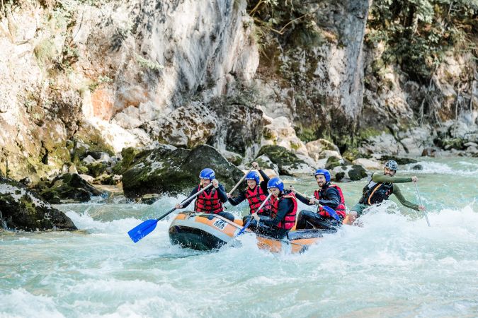 Raftinggruppe paddelt durch eine felsige Wildwasserpassage der Saalach