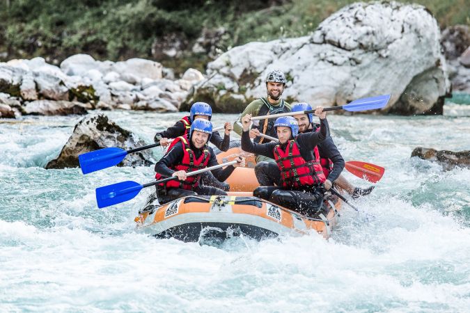Action-Rafting-Gruppe im orangefarbenen Boot zwischen Felsen